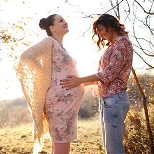 Two lesbians embracing. One is pregnant.