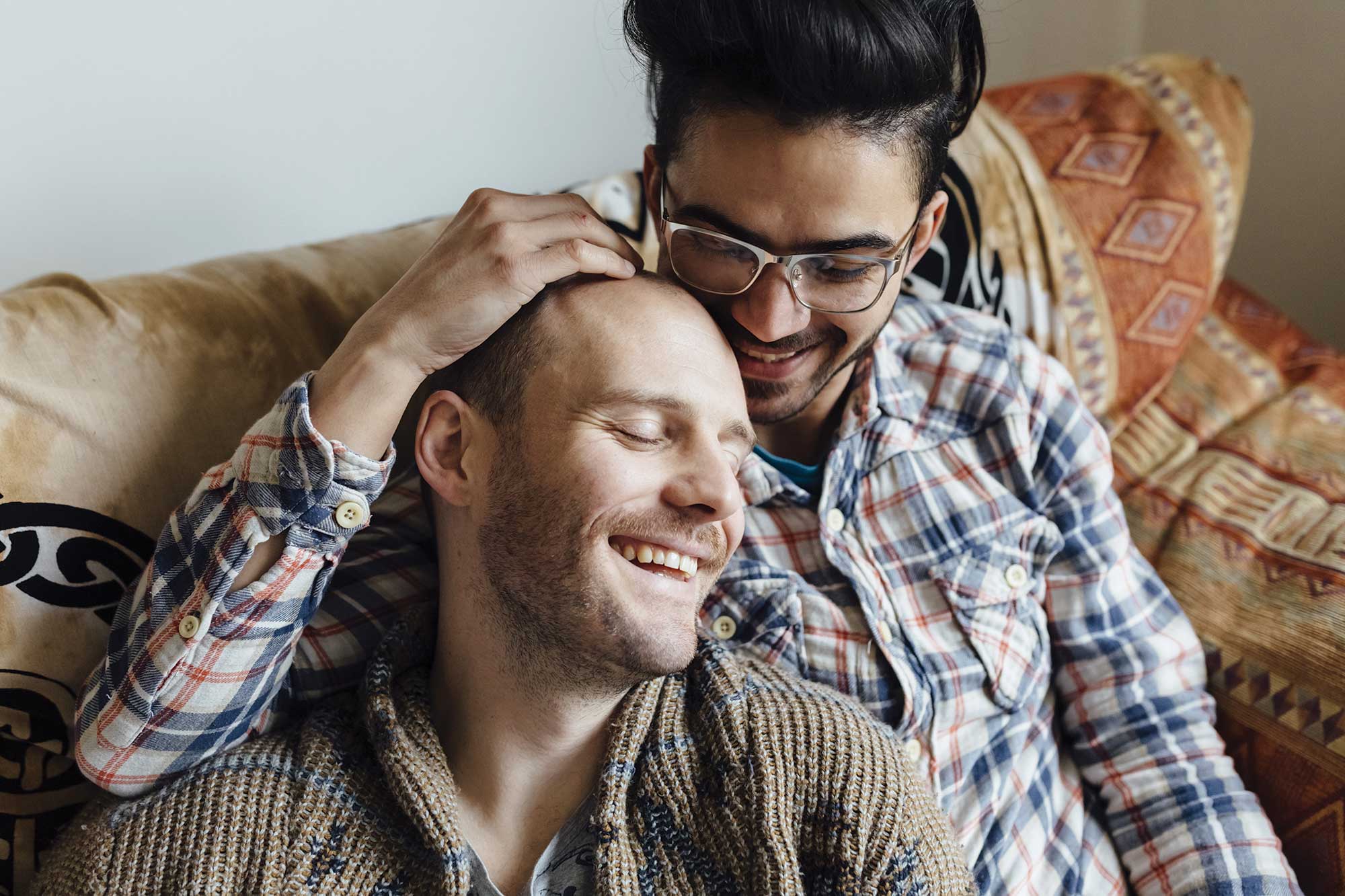 Joyful gay male couple embracing on a couch