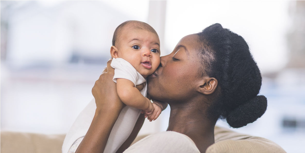 photo of black woman kissing baby
